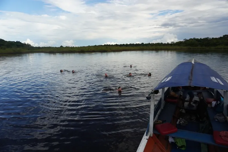 Travelers swimming in Lake Zacambú beside a boat | Amazon Jungle Trips